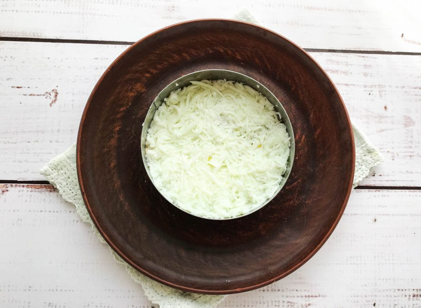 1. Этап. Салат Диана с печенью трески: Яйца очистите от скорлупы, отделите белок от желтка. Белок натрите на мелкой терке и выложите его поверх печени трески. Слой из белка смажьте майонезом.