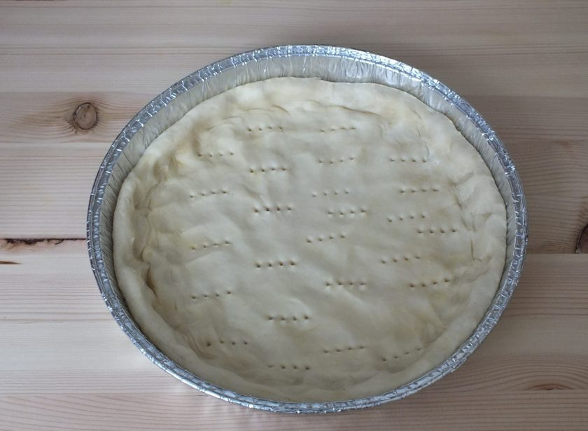 1. Этап. Пирог с черносливом и сметаной: По истечении времени достаньте тесто из холодильника. Возьмите круглую форму, в диаметре 22-26 см. Если необходимо смажьте маслом. Тесто распределите по форме. Разомните руками как можно тоньше. От толщины теста зависит время выпечки. Сделайте проколы вилкой.