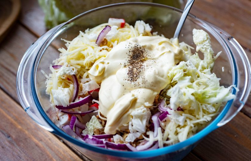 1. Этап. Салат с пекинской капустой, крабовыми палочками и сыром: Добавьте майонез, соль и черный перец. Все перемешайте.
