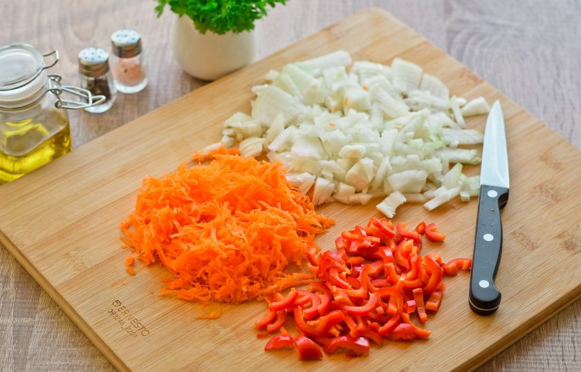 1. Этап. Рассольник с копченой колбасой и перловкой: Пока картофель варится, приготовьте овощи — очистите лук, морковь и перец. Лук нашинкуйте кубиком, морковь натрите на средней терке, перец нарежьте небольшими кусочками.