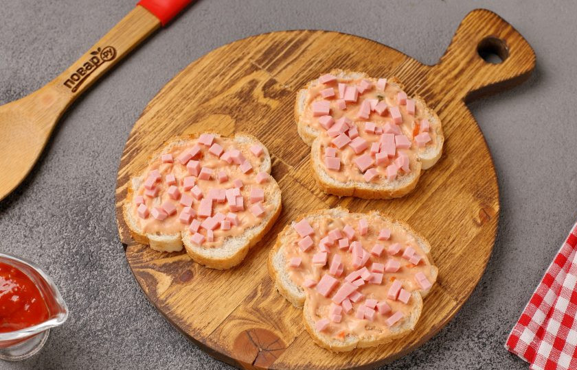 1. Этап. Мини-пицца на батоне в духовке: Сверху выложите нарезанную кубиками варёную или копчёную колбасу.