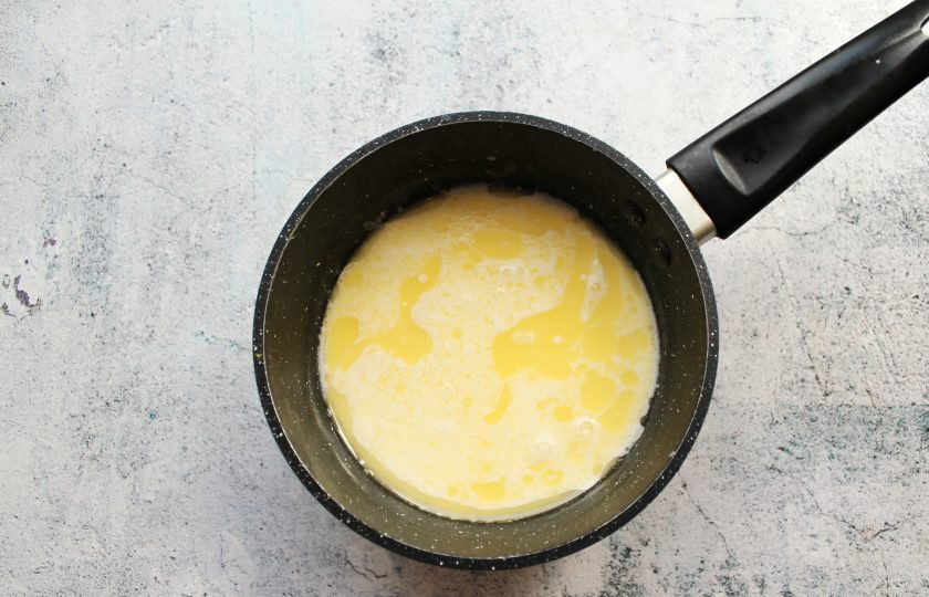 1. Этап. Белый сливочный соус: В сотейник с толстым дном выложите сливочное масло и растопите на среднем огне. Влейте сливки и убавьте огонь. Варите соус в течение 7 минут, перемешивая.