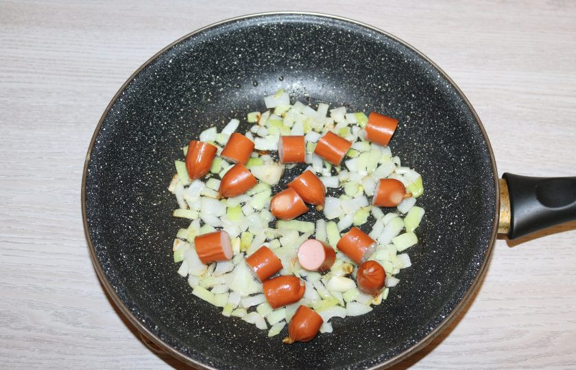 1. Этап. Фасоль по-сербски: Добавьте к луку нарезанные копчёные колбаски.