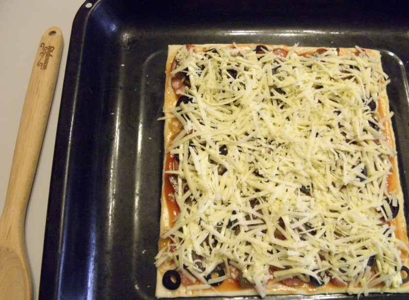 1. Этап. Пицца из слоеного теста в духовке: Полейте майонезом, а также щедро посыпьте пиццу тертым сыром. Отправьте в духовку на 10-12 минут, температура выпекания — 220 градусов.