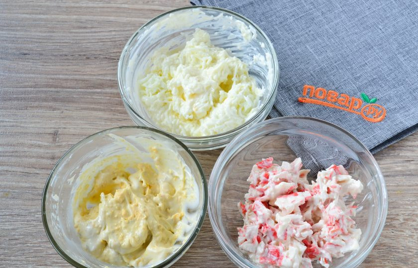 1. Этап. Закусочный торт с крабовой начинкой: Отваренные вкрутую яйца разделите на белки и желтки. Белки натрите на мелкой терке и смешайте с 1 ст. ложкой сметаны или майонеза, желтки растолките вилкой и также смешайте с 1 ст. ложкой сметаны или майонеза. Получилось 3 начинки для нашего закусочного торта.
