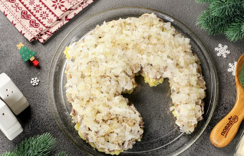 1. Этап. Селедка под шубой на год Дракона: Лук нарежьте кубиками и залейте на минуту крутым кипятком, чтобы убрать горечь. Затем слегка отожмите и выложите следующим слоем. Посолите, поперчите по желанию и смажьте майонезом.