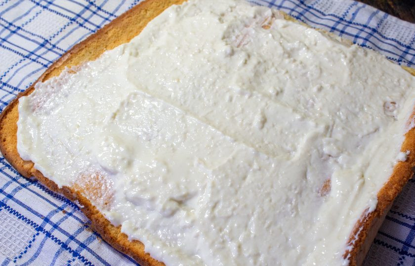 1. Этап. Рулет Рафаэлло: Разверните остывший бисквит и смажьте его ровным слоем кремом. Немного крема (3-4 столовые ложки отложите).