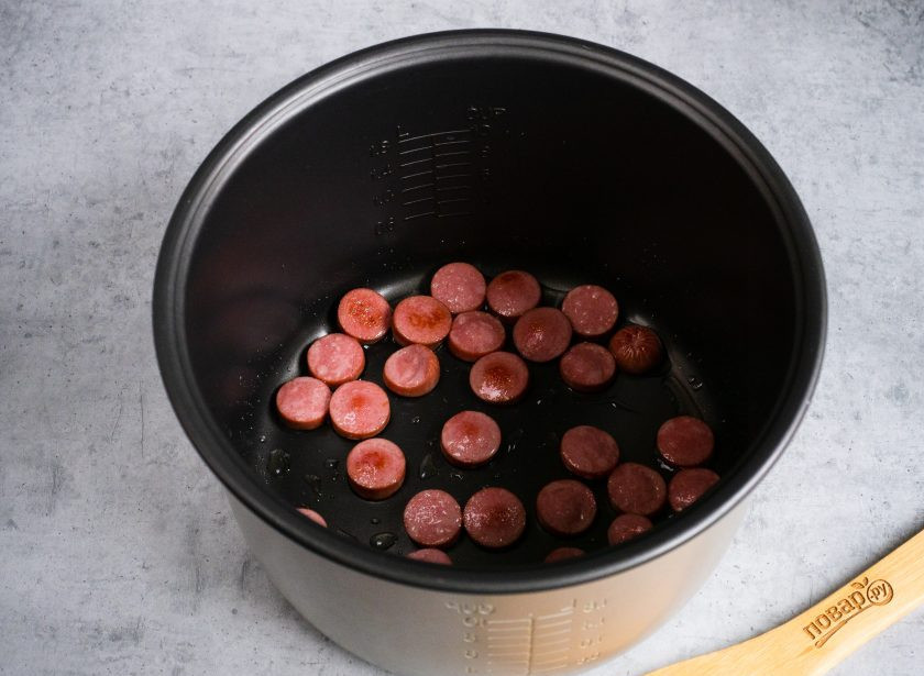 1. Этап. Омлет с сосисками в мультиварке: Сосиски нарежьте кружочками. Чашу мультиварки смажьте растительным маслом и обжарьте сосиски на режиме 