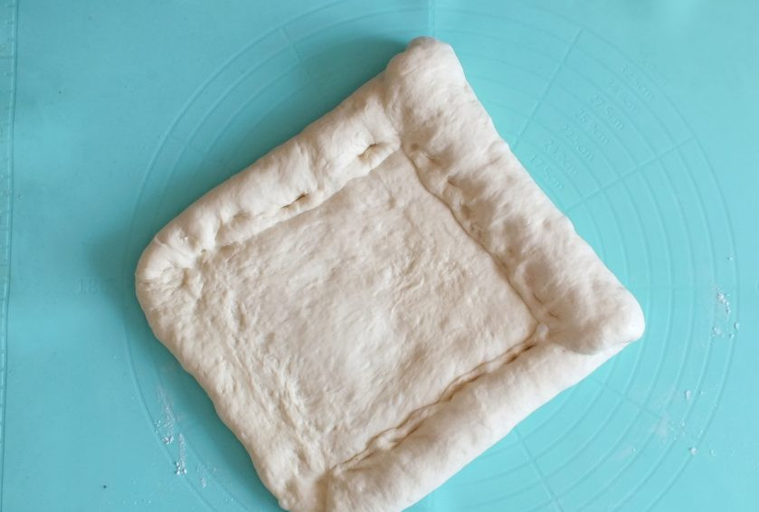 1. Этап. Хлеб в рукаве: С узкой стороны начните заворачивать рулет. После каждого оборота прижимайте пальцами место сворачивания.