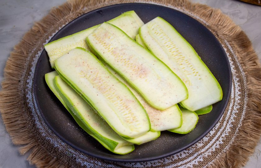 1. Этап. Лазанья из кабачков с грибами: Молодые кабачки промойте и нарежьте на тонкие пластины. Переложите в тарелку и посолите их, оставьте на 5-10 минут, чтобы они стали немного мягче. Затем ополосните от лишней соли и просушите бумажными полотенцами.