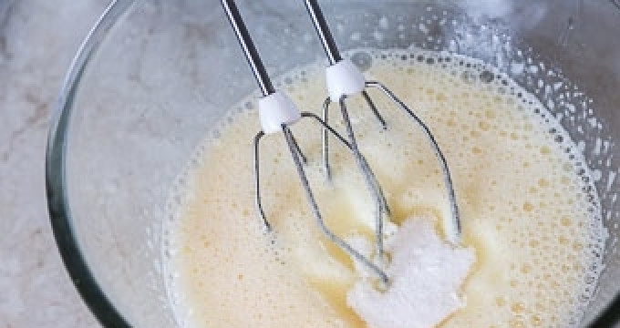 1. Этап. Кокосовое печенье без муки: Первым делом выложите сахар в глубокую ёмкость. Туда же добавьте яйца. Взбейте всё при помощи миксера до получения однородной массы (которая, к тому же, должна побелеть и увеличиться в объёме).