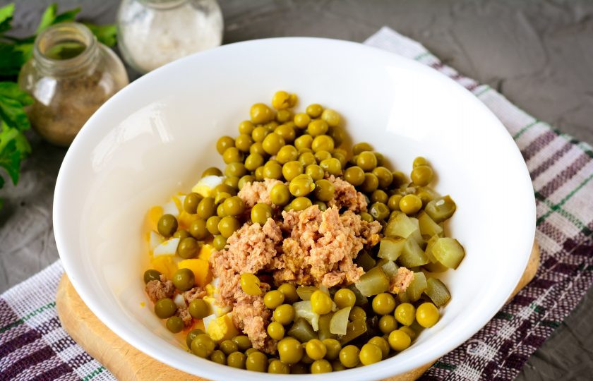 1. Этап. Салат из печени трески с горошком и огурцом: Отправьте продукты в миску и добавьте консервированный горошек.