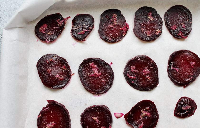 1. Этап. Вяленая свекла в духовке: Разложите кружочки свеклы на пергамент в один слой и смажьте подготовленной чесночной массой.