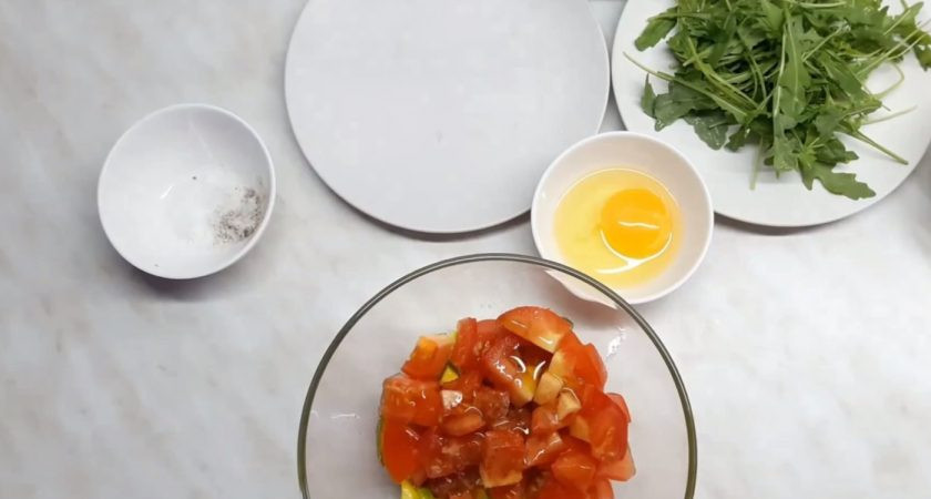 1. Этап. Вкусный салат из авокадо с яйцом пашот: 2. Помидор нарежьте такими же кусочками, не снимая с него кожуру, и добавьте к авокадо. Туда же добавьте оливковое масло, посолите и поперчите, отставьте на несколько минут для мариновки.