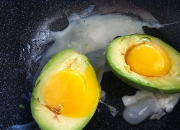 1. Этап. Яйцо в авокадо с беконом: 2. Разогрейте на сковороде масло. Выложите в него авокадо отверстиями вверх и разбейте в них по яйцу.