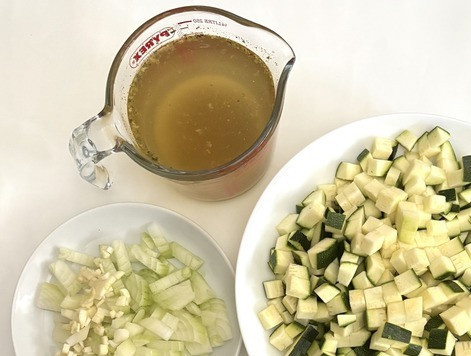 1. Этап. Холодный суп из цуккини и горошка: Залить бульон кипятком. Нарезать мелкими кубиками цуккини, также нарезать кубиками лук и чеснок.