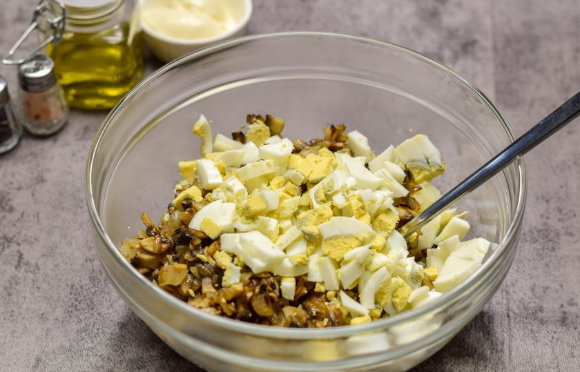 1. Этап. Салат Молдова: Куриные яйца сварите вкрутую — 12 минут, после остудите и почистите. Нарежьте яйца кубиком и переложите в салат.