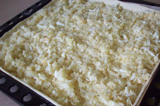 1. Этап. Пирог с капустой из слоеного дрожжевого теста: Тесто раскатываем по форме противня. Делаем в тесте бортики по краям, чтобы начинка не выпадала. Начиняем пирог яйцами с капустой.