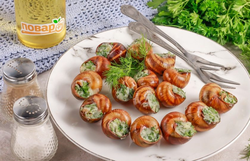 1. Этап. Виноградные улитки по-бургундски: Выложите фаршированные улитки на тарелку и запеките в микроволновке 1 минуту. Можно запечь их в духовке при 180 градусах примерно 3-5 минут, делайте так, как вам удобно. Подайте к столу блюдо теплым.