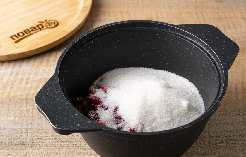 1. Этап. Варенье из тыквы и брусники: Переложите ягоды в кастрюлю с толстым дном. Добавьте сахар. Перемешайте, доведите до кипения и варите на небольшом огне 20 минут. Периодически помешивайте.