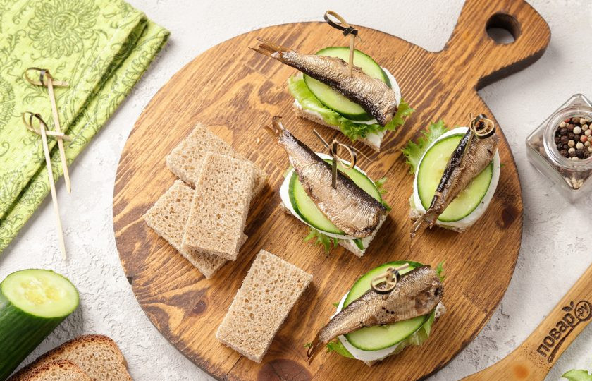 1. Этап. Канапе со шпротами и огурцом: На огурцы выложите шпроты и закрепите всё шпажками.