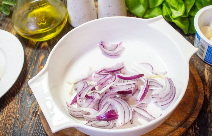 1. Этап. Салат с маринованными огурцами, помидорами и сыром: Красный лук нарежьте тонкими перьями и выложите в салатник.