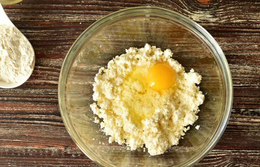 1. Этап. Сырники с кунжутом: В миску выложите творог и вбейте к нему яйцо.