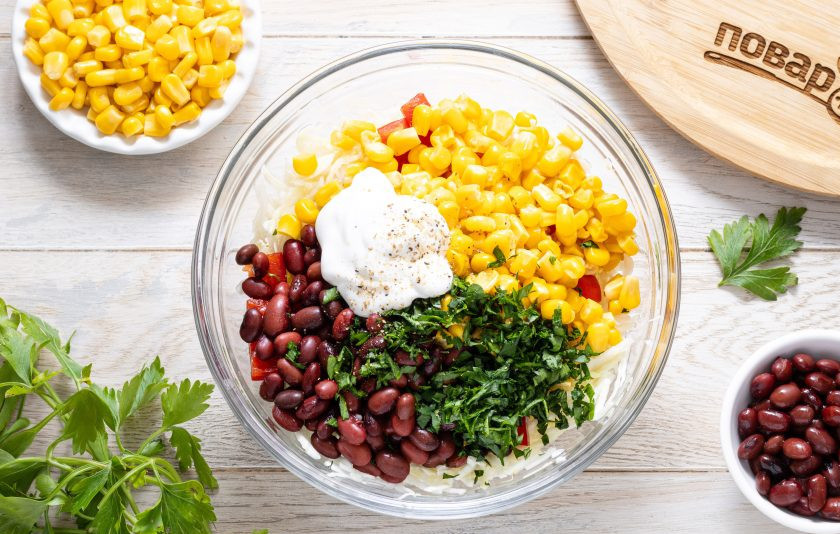 1. Этап. Салат с капустой, фасолью и кукурузой: Добавьте майонез и мелко порубленную петрушку. Поперчите по вкусу.