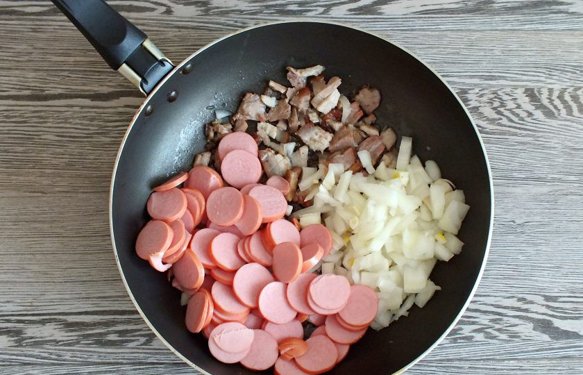1. Этап. Солянка на говяжьем бульоне: Как только сало станет прозрачным, добавьте к нему растительное масло, нарезанные сосиски и лук. Обжаривайте все вместе до мягкости лука.
