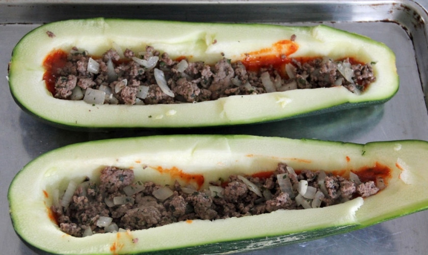 1. Этап. Говядина с кабачками в духовке: Половину кетчупа равномерно распределите по дну половинок, сверху выложите фарш.