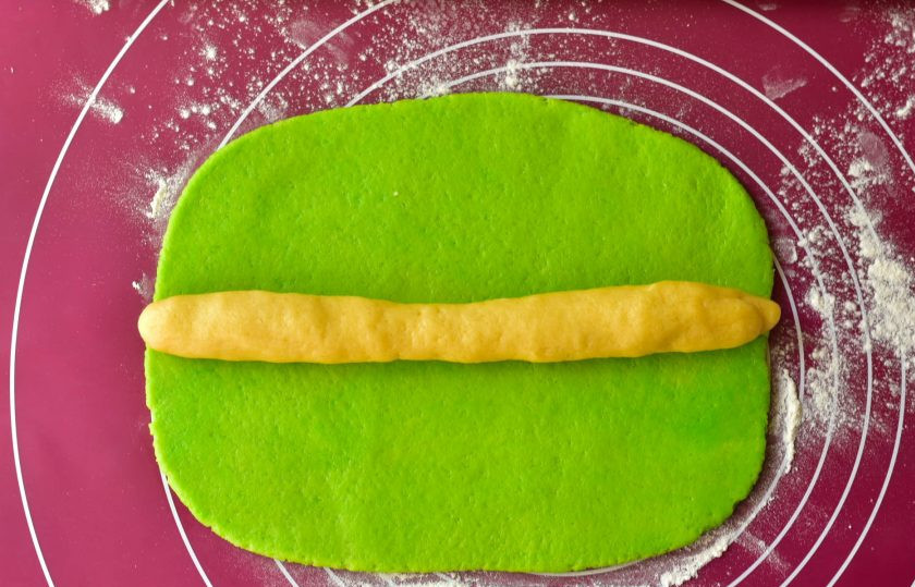 1. Этап. Печенье Киви: Скалкой раскатайте зеленую часть. Из светлой сделайте колбаску и выложите ее на зеленую.