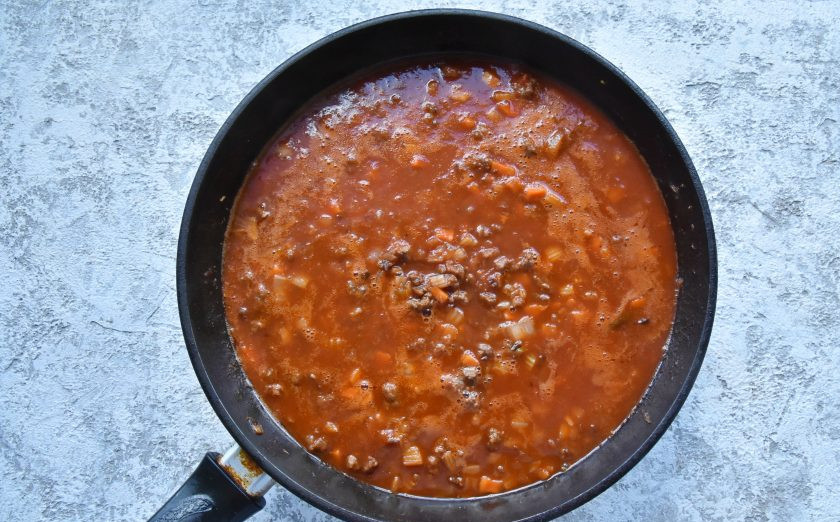 1. Этап. Лазанья с фаршем от Джейми Оливера: Влейте вино, слегка его выпарите и добавьте измельченные томаты в собственном соку или томатный домашний соус. Влейте столько же воды. Накройте сковороду крышкой и на минимальном огне тушите рагу 1,5-2 часа. Периодически открывайте крышку и помешивайте рагу.