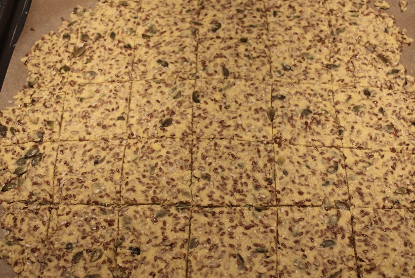 1. Этап. Кукурузные хлебцы: Готовое тесто выкладываем на противень, затянутый пергаментом, и разравниваем его при помощи ложки, делим ножом на квадратики.