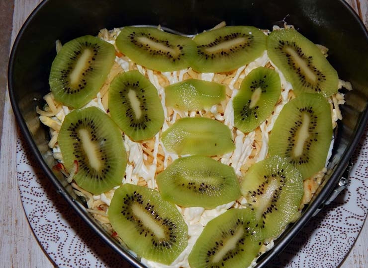 1. Этап. Салат с киви и ветчиной: Украсьте кружочками киви. Поставьте салат пропитываться на один час в холодильник.