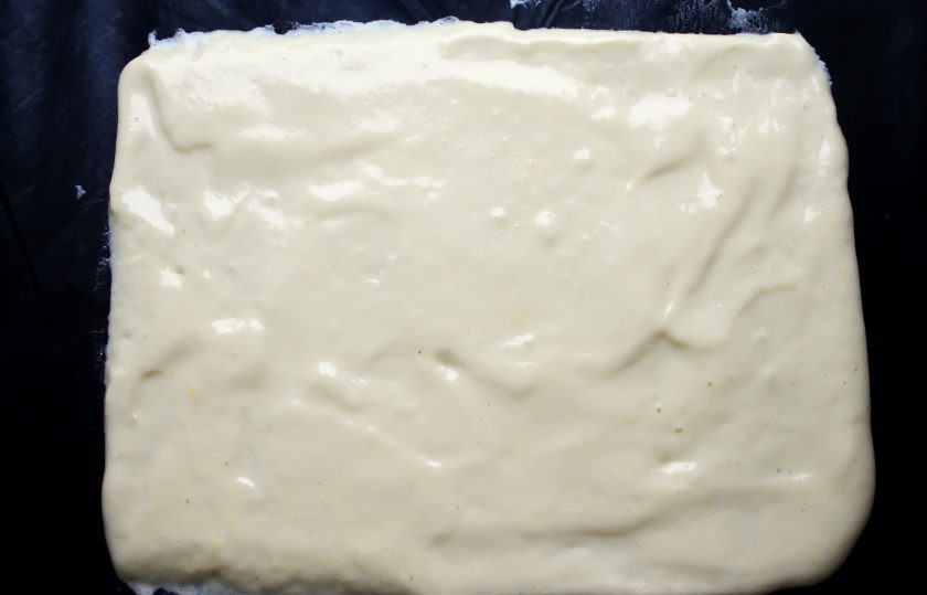 1. Этап. Бисквитный рулет с киви: Противень застелите пергаментом или ковриком для запекания. Вылейте на него тесто и разровняйте в прямоугольник.