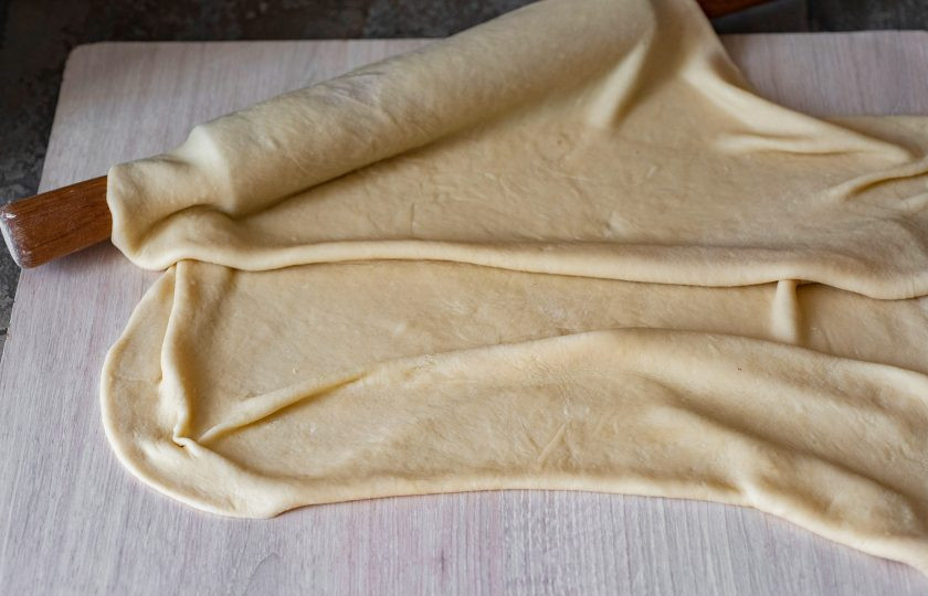 1. Этап. Штрудель с яблоками и вишней: Рабочую поверхность припылите мукой и раскатайте тесто в максимально тонкий пласт.