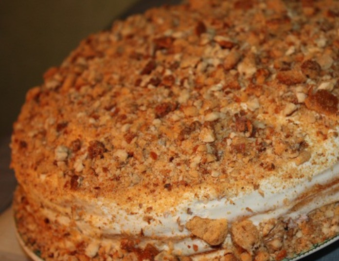 1. Этап. Медовый пирог с грецкими орехами: Оставшимся кремом полностью обмажьте торт и обильно посыпьте орехами и крошкой печенья. Прежде чем подавать на стол дайте торту хорошо пропитаться. Для этого поставьте на пару часов в холодильник.