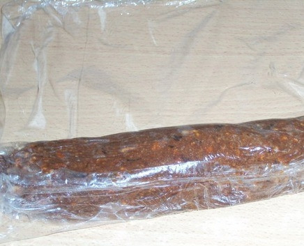 1. Этап. Шоколадная колбаса со сгущенкой: Все ингредиенты тщательно размешайте. Делать это лучше прямо руками. Сформируйте из получившейся массы колбаску. Масса должна быть пластичной, но не липкой. Выложите колбаску на пищевую пленку.