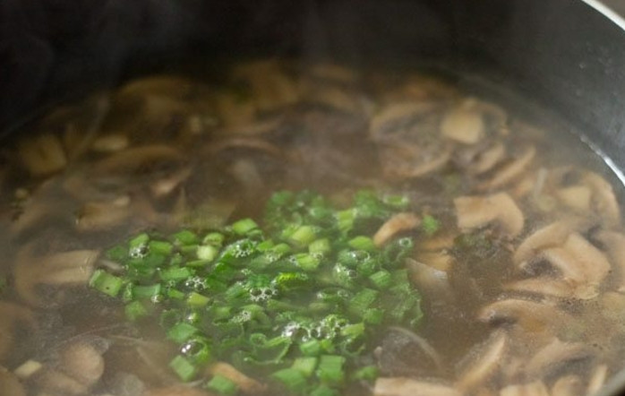 1. Этап. Рецепт супа с грибами: Накройте суп крышкой и варите на медленном огне 15 минут. Затем добавьте остальной зеленый лук.