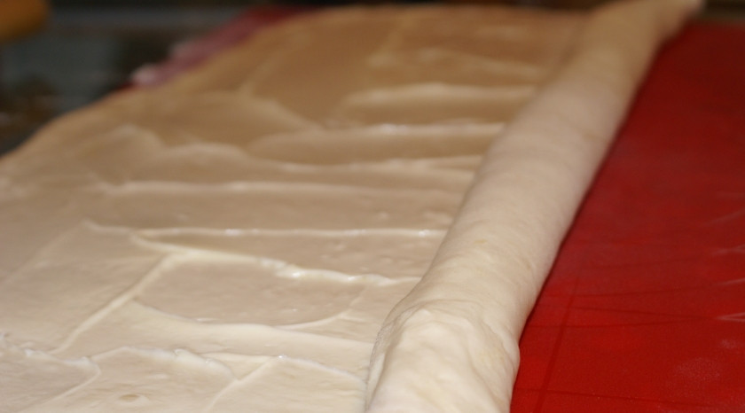 1. Этап. Хачапури из слоеного теста: Раскатайте тесто, смажьте маслом, закатайте в рулет.