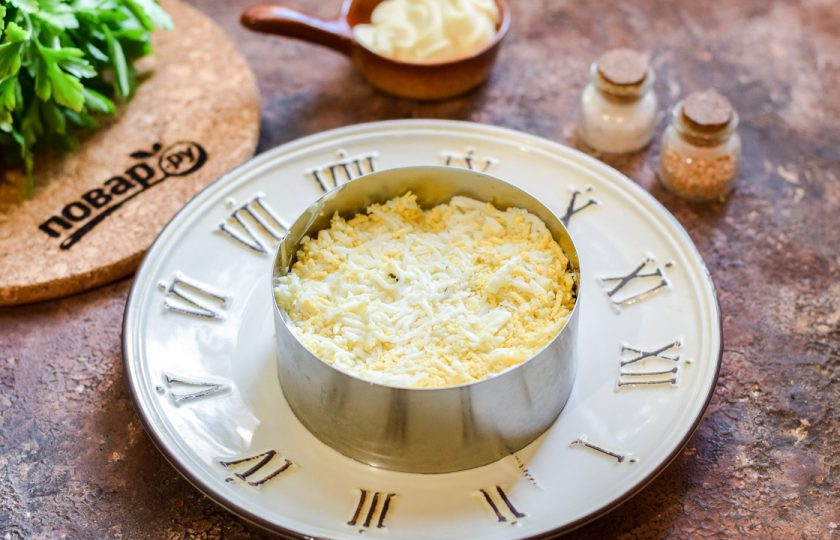 1. Этап. Салат Полтавский: Куриные яйца почистите и натрите на мелкой терке. Выложите яйца поверх рыбы, смажьте майонезом.