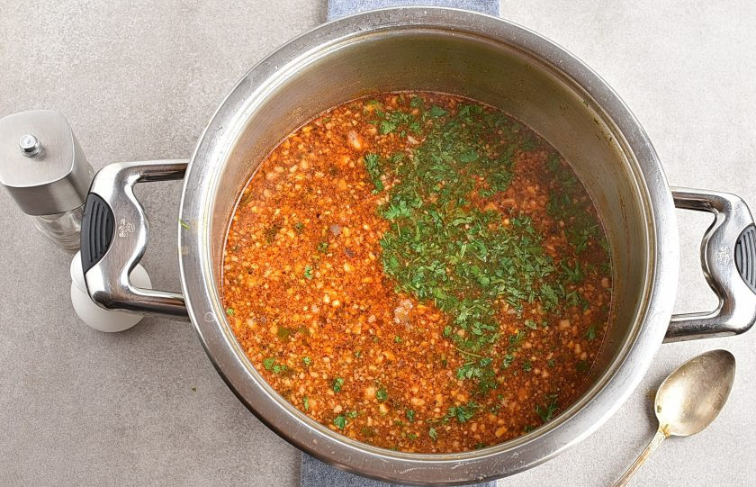 1. Этап. Харчо из говядины с ткемали: Попробуйте суп на соль. Выложите остатки шинкованной зелени, выключите нагрев и накройте суп крышкой. Дайте настояться минут 20.