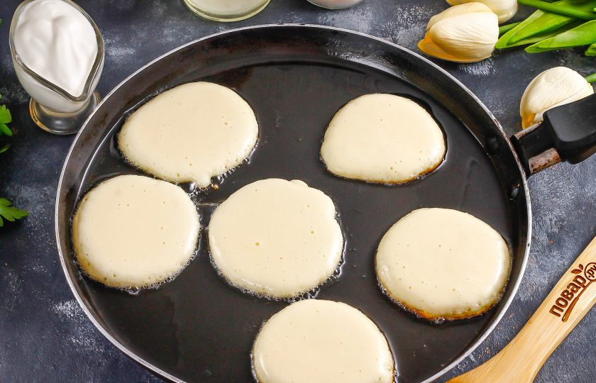 1. Этап. Торт из оладий: Прогрейте в сковороде растительное масло и убавьте нагрев практически до минимального, так как оладьи будут очень быстро выпекаться. Выложите столовой ложкой части теста в горячее масло.