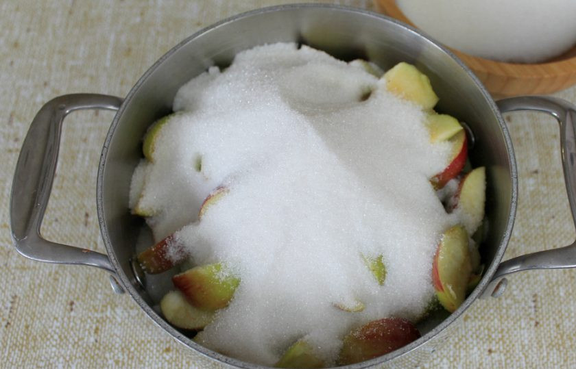 1. Этап. Варенье из яблок с курагой: К яблокам добавляем сахар и ставим кастрюлю на минимальный огонь. Можно перемешать, чтобы сахар быстрее растворился.