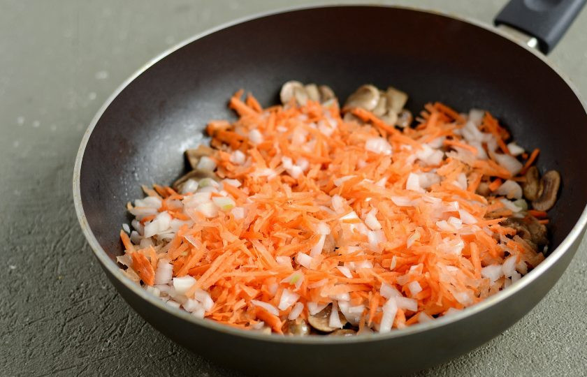 1. Этап. Макароны с капустой: Добавьте в сковороду тертую морковь и лук кубиками. Обжарьте их до мягкости.
