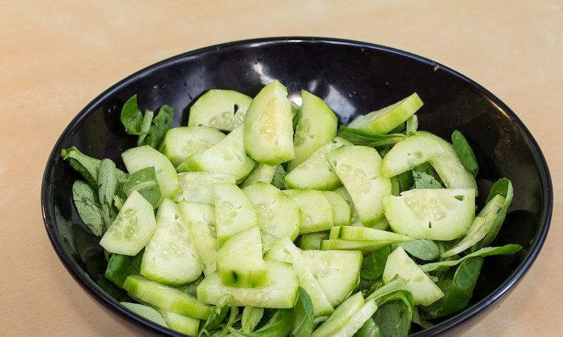 1. Этап. Легкий салат с курицей: Огурец режем полукольцами и кладем к листьям салата.