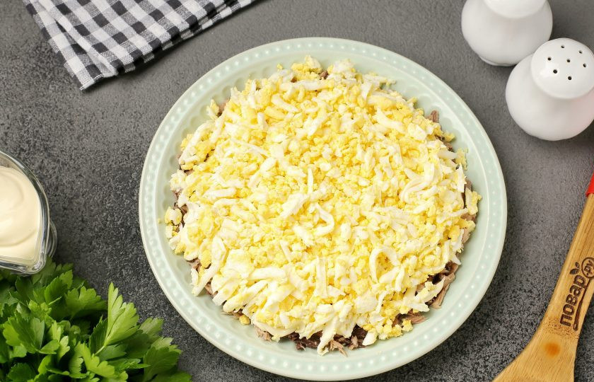 1. Этап. Слоёный салат с тунцом, помидорами, сыром и яйцами: Далее выложите тёртые на крупной тёрке яйца. Посолите, поперчите и смажьте майонезом.