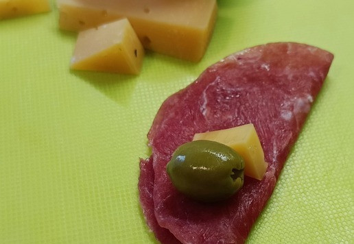 1. Этап. Закуска с сыровяленой индейкой: На свернутый ломтик сыровяленого мяса положить по кусочку сыра и оливку.