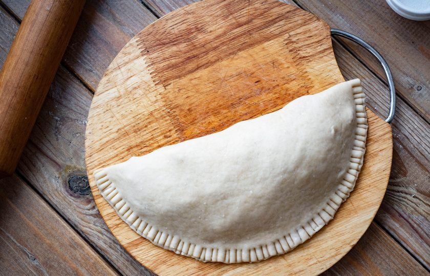 1. Этап. Кальцоне с ветчиной: Свободной частью раскатанного теста накройте часть теста с начинкой. Края закрепите пальцами или вилкой. С оставшейся частью теста и начинкой поступите в точности также.