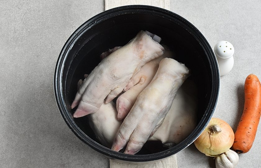 1. Этап. Холодец из свиных ножек в мультиварке: Самое сложное и ответственное — хорошо вымыть и отскоблить ножки. Чистые ножки выложите в чашу мультиварки, залейте холодной водой на палец выше ножек. В режиме 